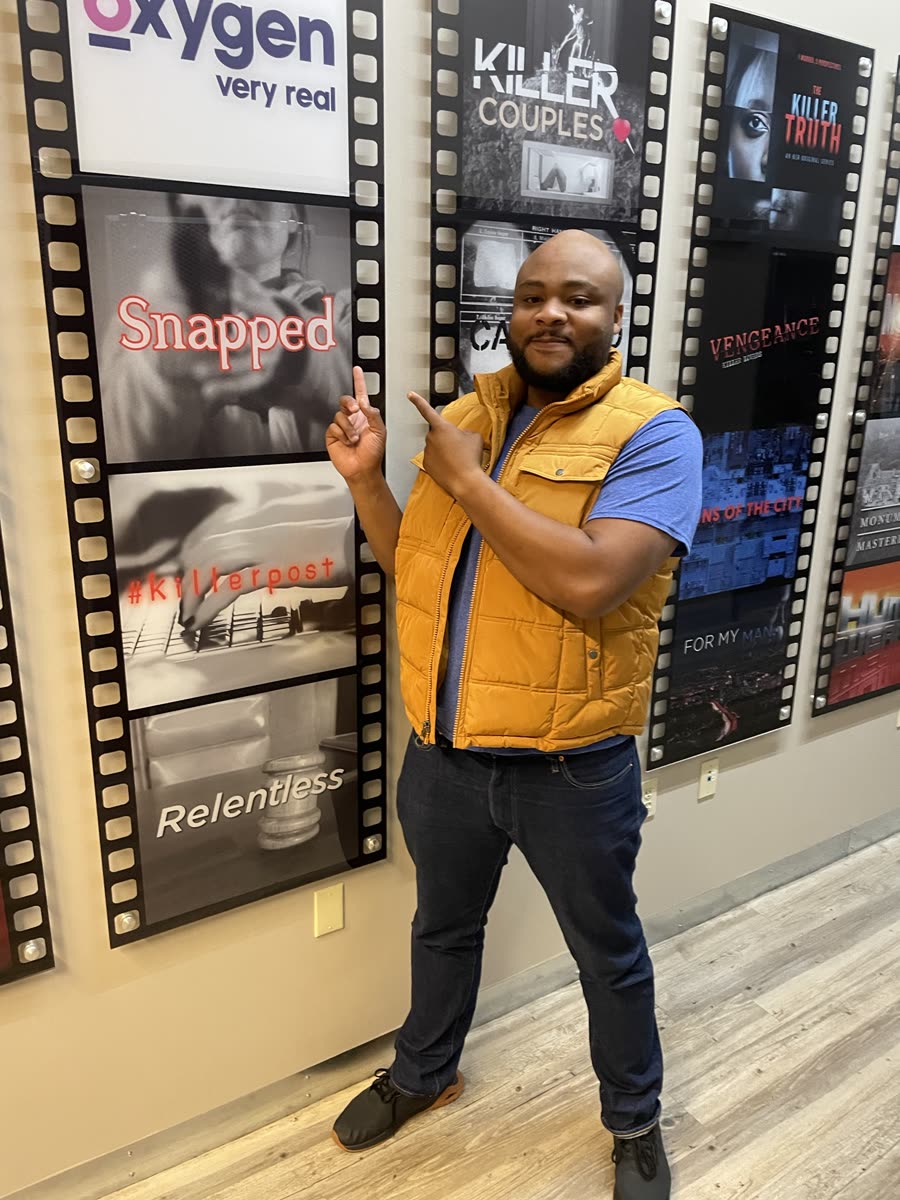 Scottie Stowe pointing at the Snapped poster on the Oxygen show wall