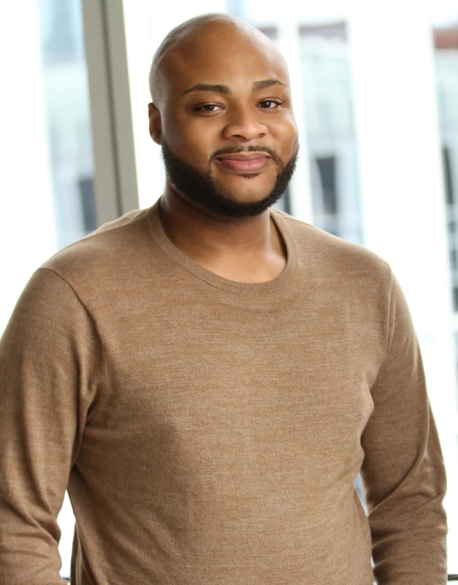 Smiling commercial headshot of Scottie Stowe in a tan sweater
